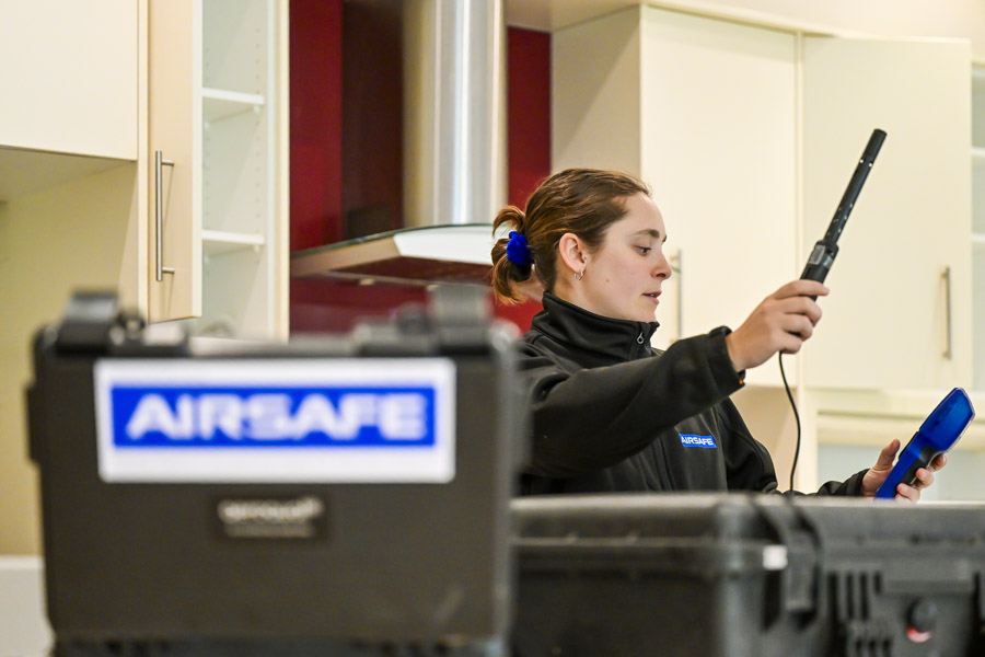 Airsafe consultant taking indoor air quality readings with a handheld Aeroqual monitor