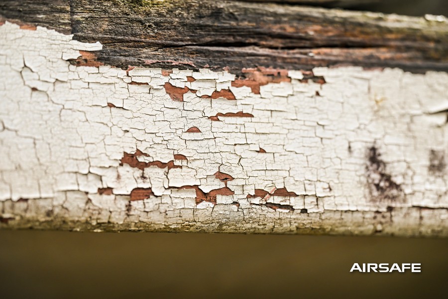 Cracked and peeling paint on the timber beam of an older home