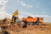 Excavator loading soil into a dump truck at an earthworks site