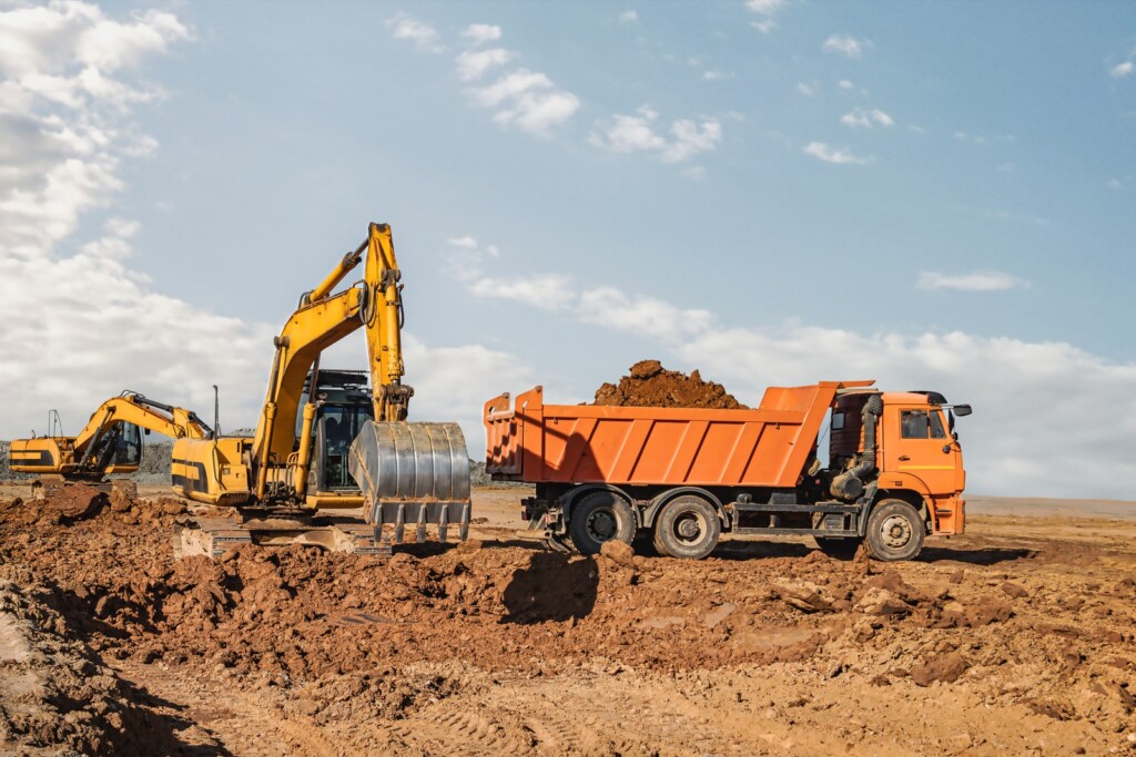 Excavator loading soil into a dump truck at an earthworks site
