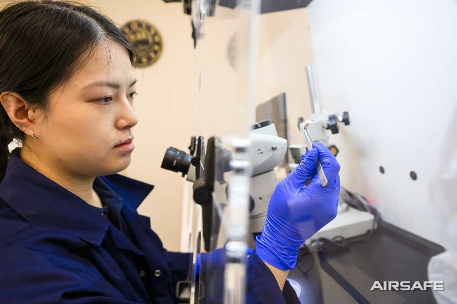 Airsafe analyst examining a fragment of suspected asbestos cement sheet at the stereo microscope in the Beaconsfield laboratory