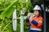 Airsafe consultant in hi-vis and hard hat checking a post-mounted asbestos air monitoring pump on site.