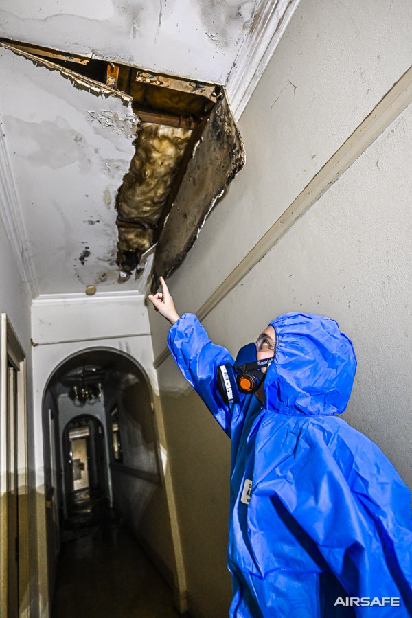 An Airsafe consultant pointing to a collapsed section of water-damaged ceiling in a hallway
