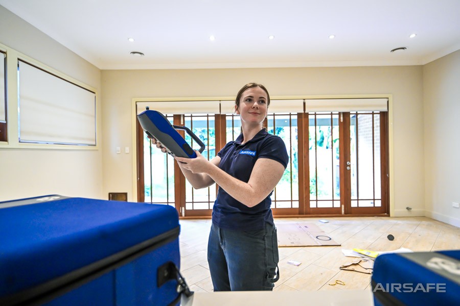 Airsafe consultant using a handheld DustTrak DRX dust monitor in a house under renovation