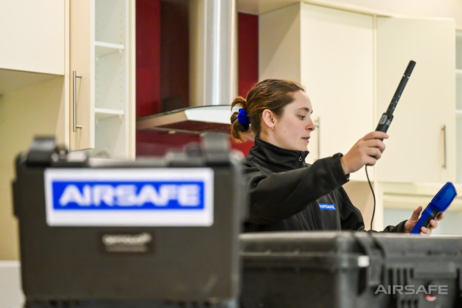Airsafe consultant taking indoor air quality readings with a handheld Aeroqual monitor