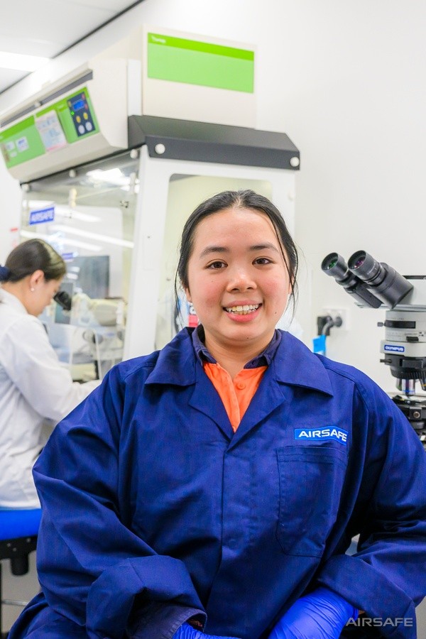 Airsafe laboratory analyst with colleagues working behind her