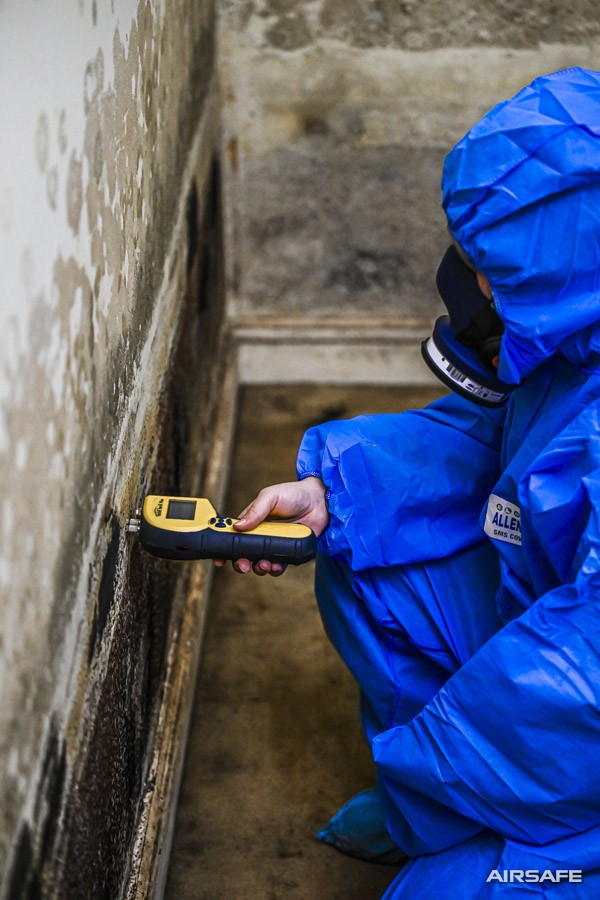 An Airsafe consultant checking a mould-affected wall with a moisture meter
