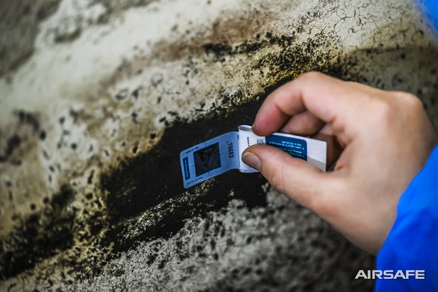 An Airsafe consultant taking a tape-lift sample from black mould on a wall