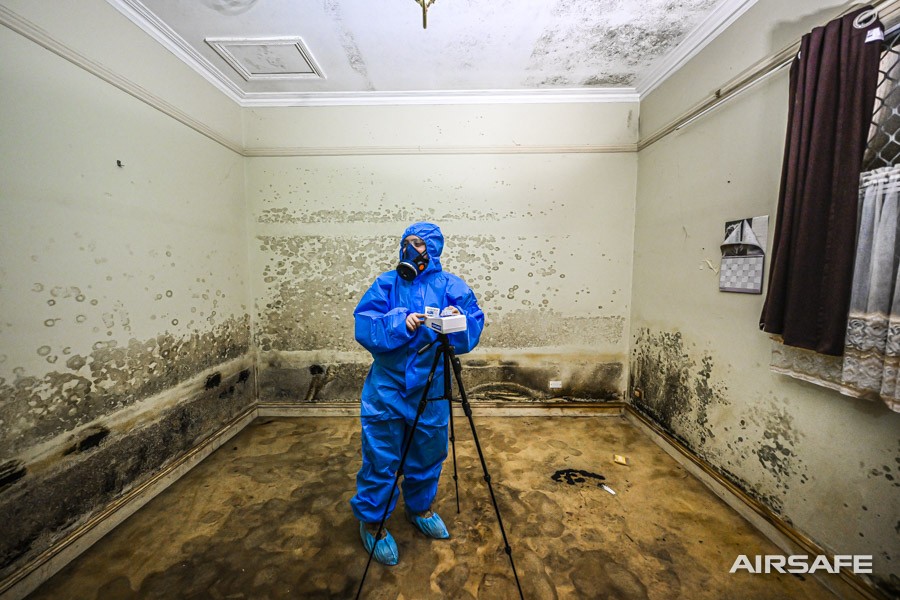 An Airsafe consultant setting up tripod air sampling in a severely mould-damaged room