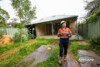 Airsafe consultant carrying air sampling equipment at the rear of an older brick home