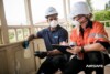 Two people in hard hats and masks inspect a timber verandah wall panel
